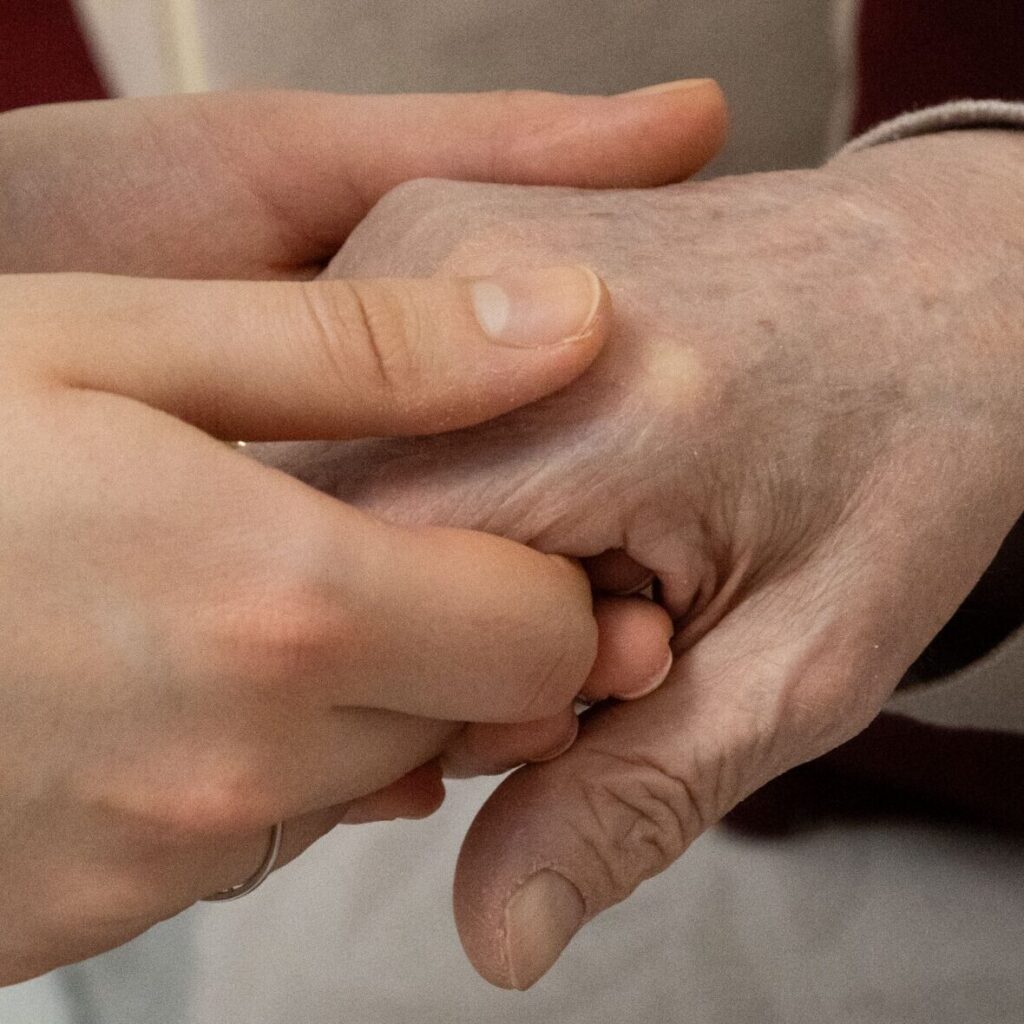 gentle hand holding elderly person with dementia
